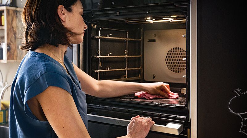 Image of a woman cleaning the inside of an integrated oven appliance