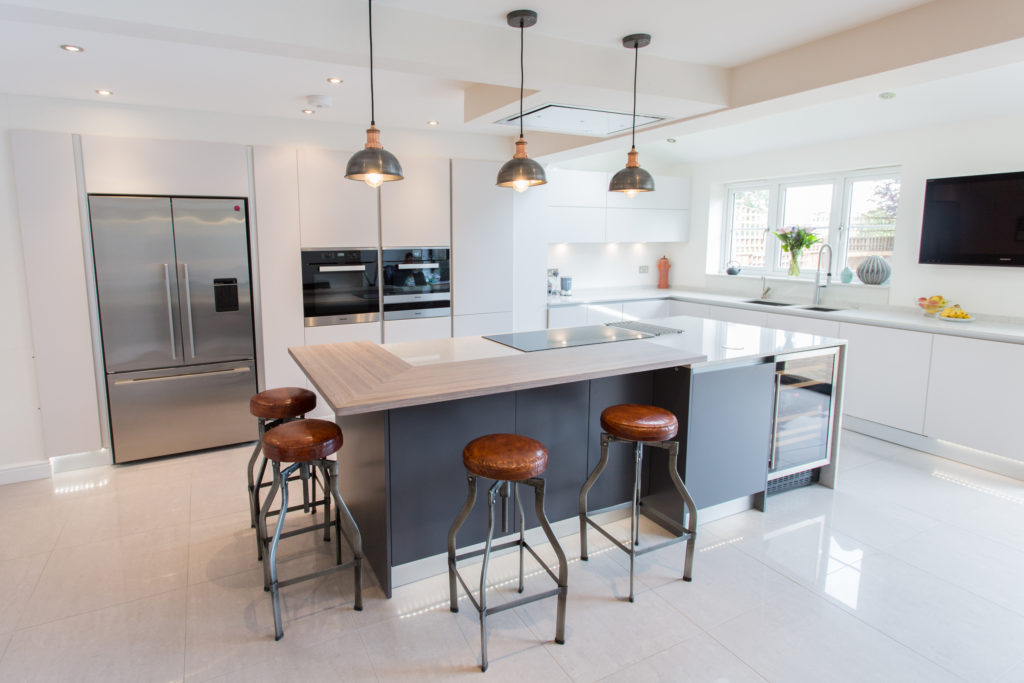 Image of a white handleless kitchen design with blue kitchen units and contrasting accessories.
