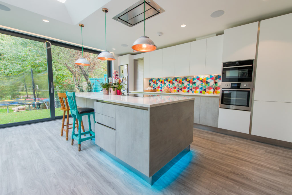 Image of handleless kitchen design with a neutral colour palette with bold contrasting colours and blue recessed lighting.