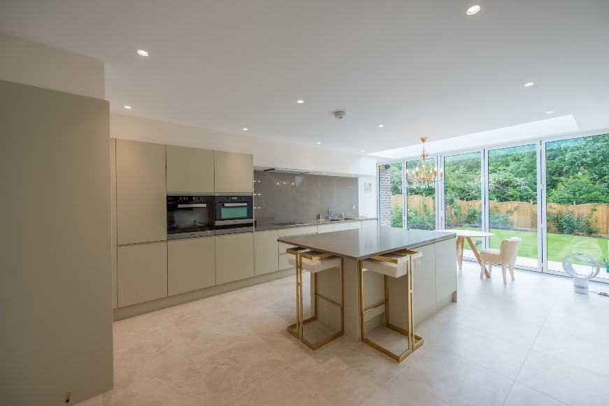 Image of an open-plan and handleless kitchen design with a neutral colour palette of creams.