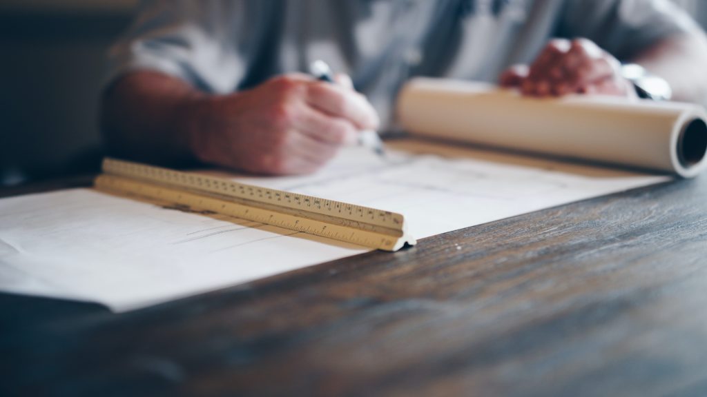 Image of a man drawing schematics on a scroll to suggest preparing for obtaining planning permission.
