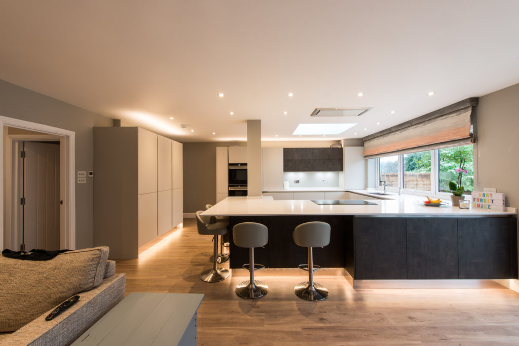 An open plan kitchen with light wall units and dark base units