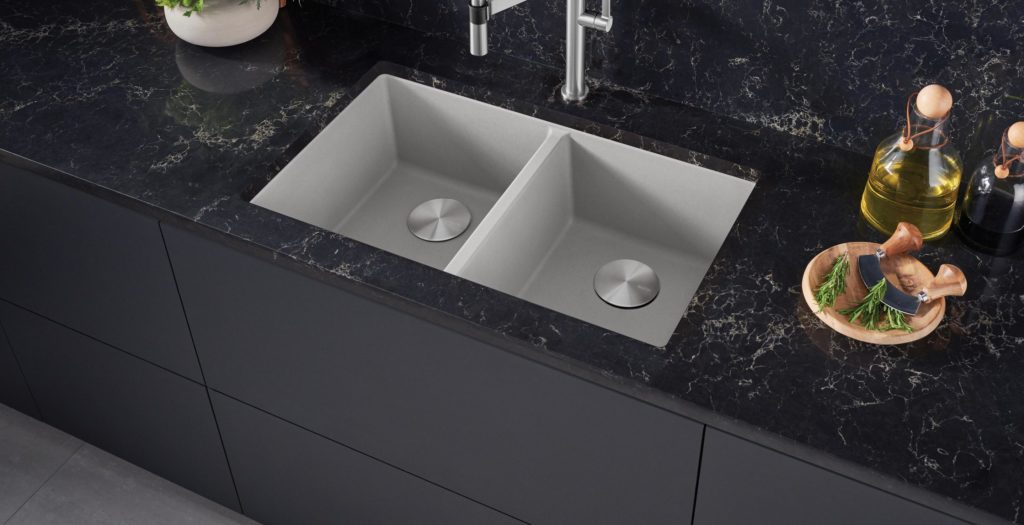 A pale grey double sink inset into a black veined marble worktop