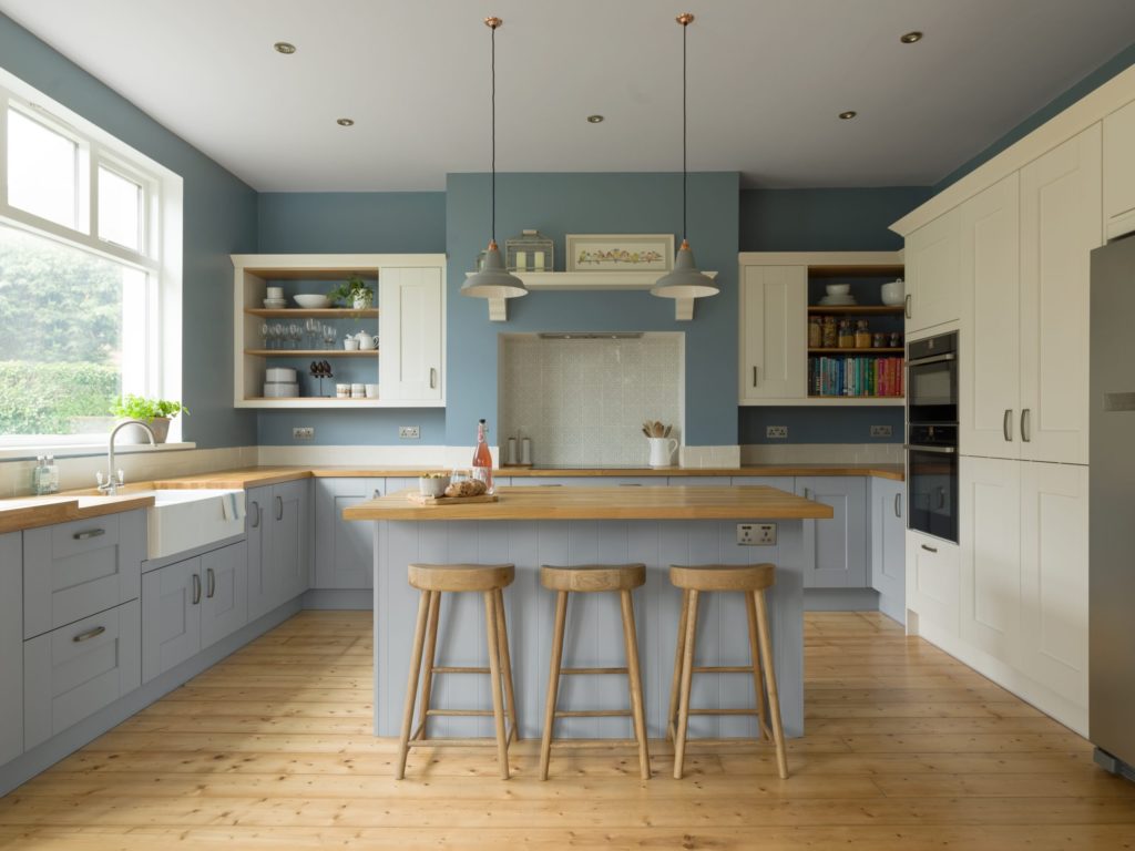 A baby blue kitchen with wooden accents, island and breakfast stools