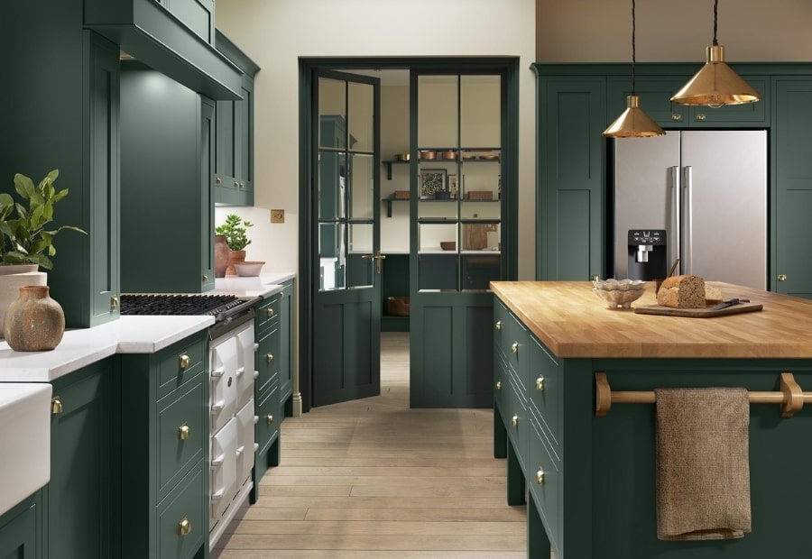 green tradtiional kitchen with contrasting white and wood worktops and brass handles